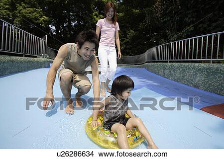 A couple playing with their son at water slide View Large Photo Image Picture - A couple playing with their son at water slide. Fotosearch
