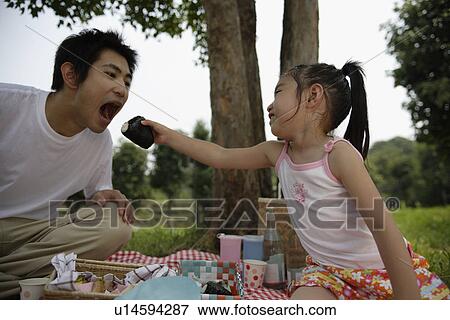 Stock Photo - A daughter feeding a rice ball to her father. Fotosearch