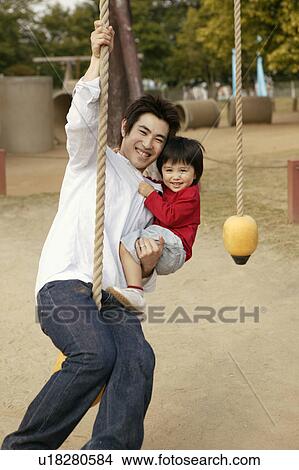 Picture - A father swings holding a rope with his son. Fotosearch