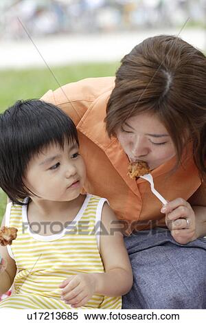 Stock Photography - A mother and son eating fried chicken. Fotosearch