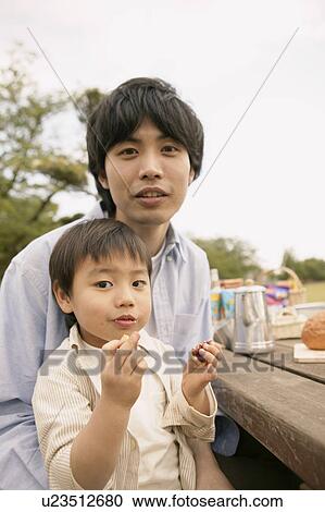 A small boy sitting on his fathers lap as he eats on View Large Photo Image Stock Image - A small boy sitting on his fathers lap as he eats on. Fotosearch