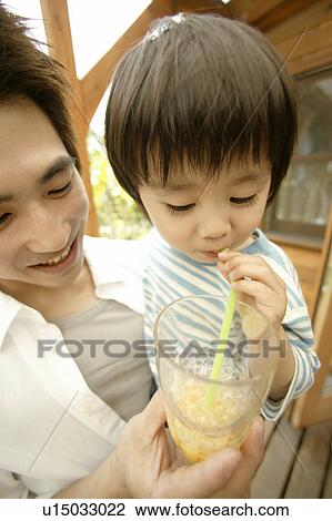 Stock Image - A young boy makes bubbles out of the juice he is drinking. Fotosearch