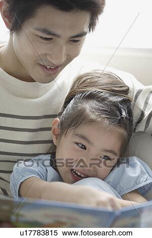 A young father reading a book to his daughter View Large Photo Image Stock Photography - A young father reading a book to his daughter. Fotosearch