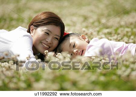 Mother and a daughter lying in a garden amidst flowers View Large Photo Image Stock Image - Mother and a daughter lying in a garden amidst flowers. Fotosearch