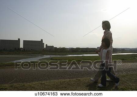 Mother and daughter walking along pathway View Large Photo Image Stock Image - Mother and daughter walking along pathway. Fotosearch
