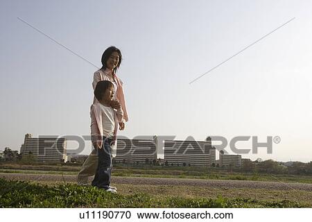 Mother and daughter walking along pathway View Large Photo Image Stock Image - Mother and daughter walking along pathway. Fotosearch
