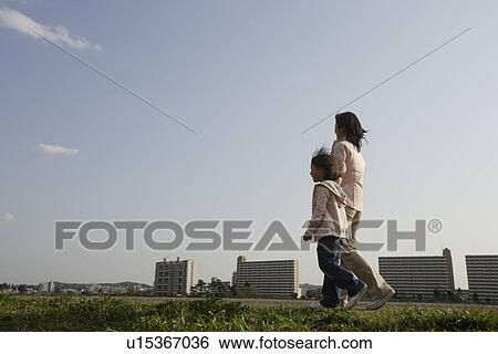 Stock Photograph - Mother and daughter walking along pathway. Fotosearch