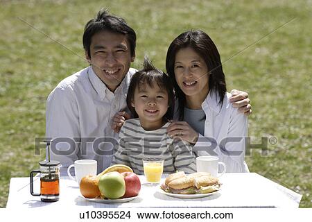 Picture - Portrait of a family smiling in garden by breakfast table. Fotosearch