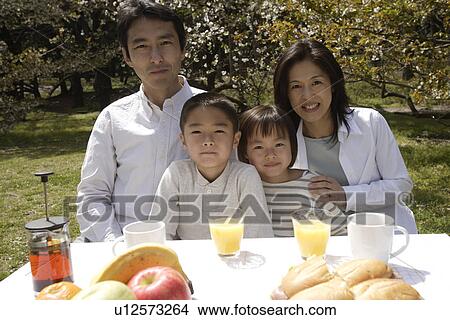 Portrait of a family smiling in garden by breakfast table View Large Photo Image Picture - Portrait of a family smiling in garden by breakfast table. Fotosearch