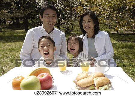 Portrait of a family smiling in garden by breakfast table View Large Photo Image Stock Photo - Portrait of a family smiling in garden by breakfast table. Fotosearch