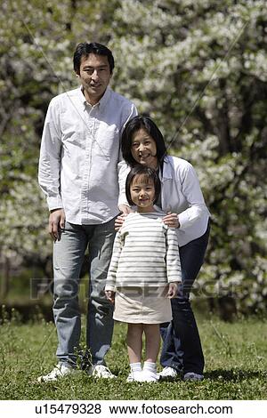 Stock Photo - Portrait of a family standing together in garden. Fotosearch
