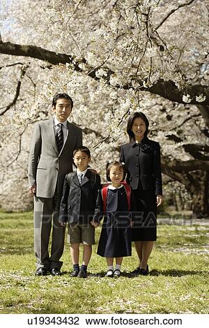 Stock Image - Portrait of a family standing under tree. Fotosearch