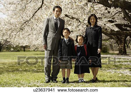 Stock Image - Portrait of a family standing under tree. Fotosearch