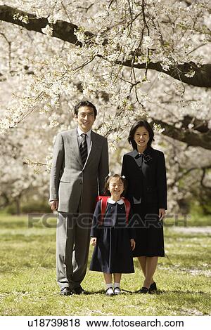 Stock Photo - Portrait of a family standing under tree. Fotosearch