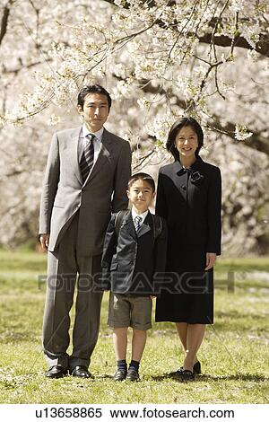 Stock Photography - Portrait of a family standing under tree. Fotosearch