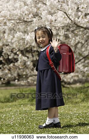 Stock Image - Portrait of a girl in school uniform waving her hand. Fotosearch