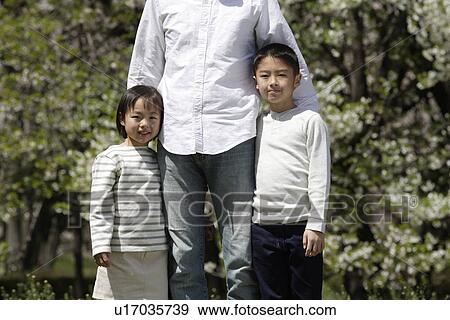 Stock Photo - Portrait of girl and boy standing with father. Fotosearch