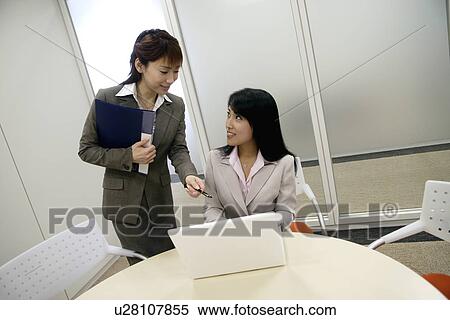 A woman points out on the screen of laptop as the other stares at her View Large Photo Image Stock Photography - A woman points out on the screen of laptop as the other stares at her. Fotosearch
