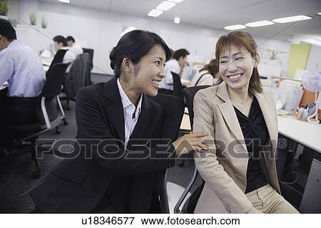 A woman sharing a joke with her colleague in the office View Large Photo Image Stock Photo - A woman sharing a joke with her colleague in the office. Fotosearch