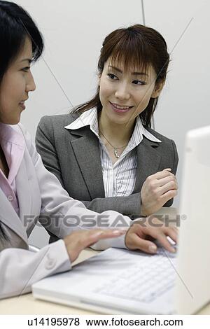 Stock Photo - Two women enjoying themselves as they work on the laptop. Fotosearch