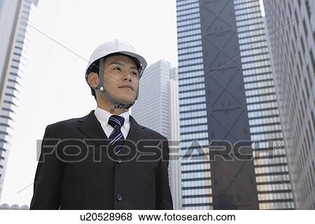 Stock Photo - Businessman holding his hard hat, portrait. Fotosearch