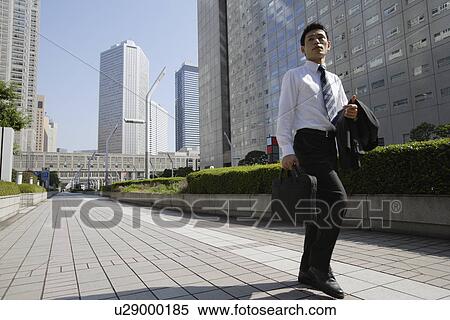 Businessman walking on a sidewalk View Large Photo Image Stock Photography - Businessman walking on a sidewalk. Fotosearch