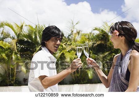 Stock Photo - A young couple toasting wineglass. Fotosearch