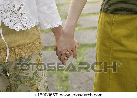 Stock Photo - Front view of two women holding each others hand. Fotosearch