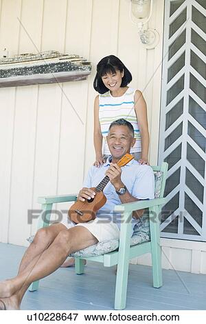 Stock Photo - Man holding guitar and woman standing behind him. Fotosearch