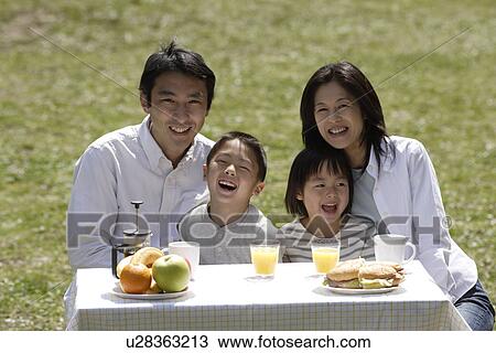 Portrait of a family smiling in garden by breakfast table View Large Photo Image Stock Image - Portrait of a family smiling in garden by breakfast table. Fotosearch