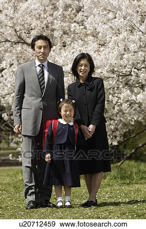 Stock Photo - Portrait of a family standing under tree. Fotosearch