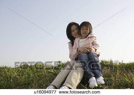 Portrait of a mother sitting with daughter on grass View Large Photo Image Stock Photo - Portrait of a mother sitting with daughter on grass. Fotosearch