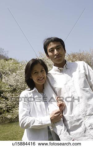 Stock Photograph - Portrait of a young couple smiling in garden. Fotosearch