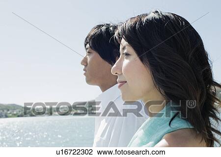 Stock Image - Profile of a young couple standing together. Fotosearch