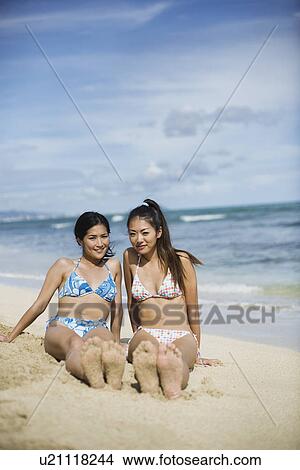Picture - Young women sitting on sand smiling. Fotosearch