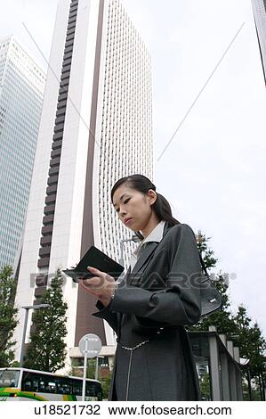 Stock Image - A young businesswoman checking schedule. Fotosearch