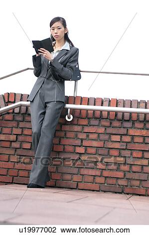 Stock Image - A young businesswoman checking schedule. Fotosearch