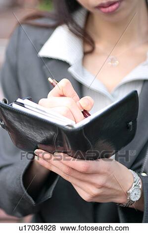 Stock Photo - A young businesswoman checking schedule, close-up. Fotosearch