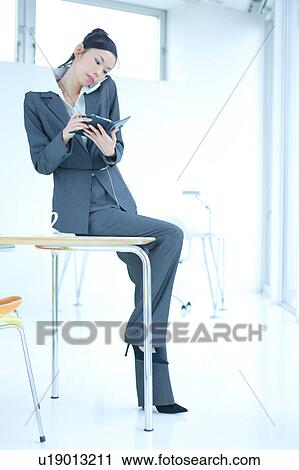 Stock Image - A young businesswoman talking over mobile phone in office. Fotosearch