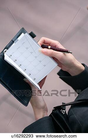 Stock Image - A young woman checking schedule, close-up. Fotosearch
