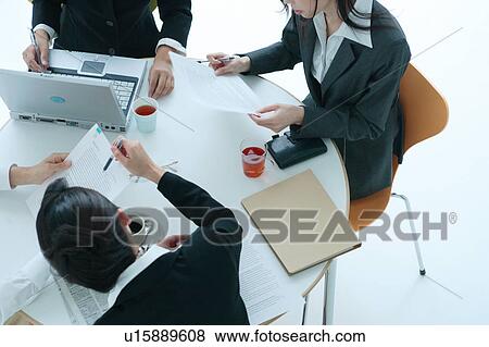 Stock Photo - Four young women having meeting in office, close-up. Fotosearch