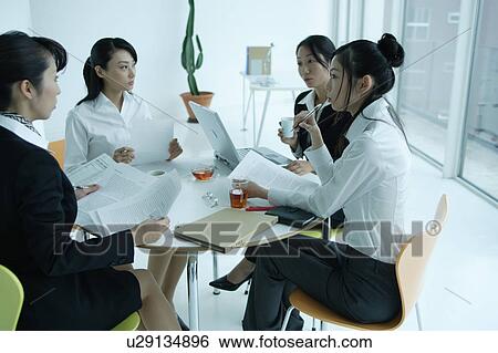 Four young women having meeting in office View Large Photo Image Stock Photograph - Four young women having meeting in office. Fotosearch