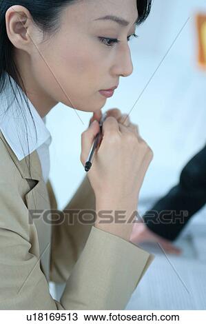 Stock Image - One young woman pondering in office. Fotosearch