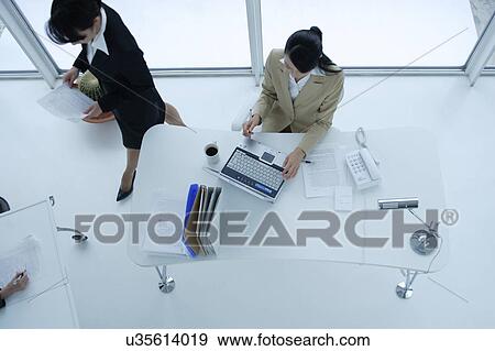 Stock Photo - Small group of young women working in office, high angle view. Fotosearch