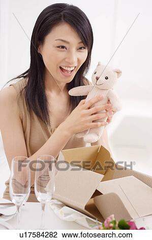 Stock Image - A smiling young woman holding Teddy Bear. Fotosearch