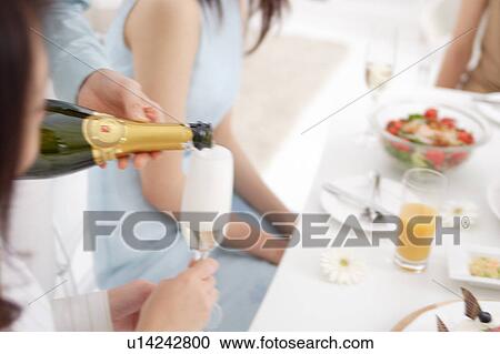 A woman is pouring champagne into glass View Large Photo Image Stock Image - A woman is pouring champagne into glass. Fotosearch