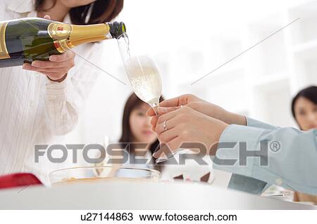 A woman is pouring champagne into glass View Large Photo Image Stock Image - A woman is pouring champagne into glass. Fotosearch