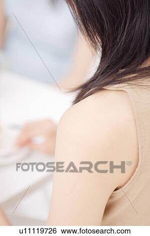 A young woman at table, rear view View Large Photo Image Stock Photograph - A young woman at table, rear view. Fotosearch
