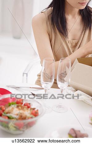 Stock Image - A young woman opening a present. Fotosearch