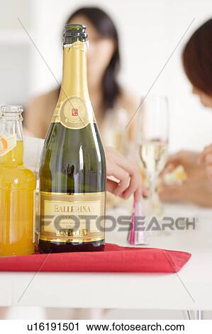 Bottle of champagne with young women in the background View Large Photo Image Stock Image - Bottle of champagne with young women in the background. Fotosearch